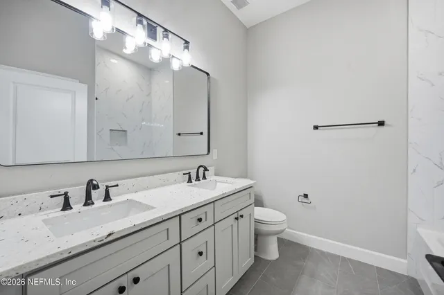 a bathroom with a granite countertop sink a toilet and a mirror