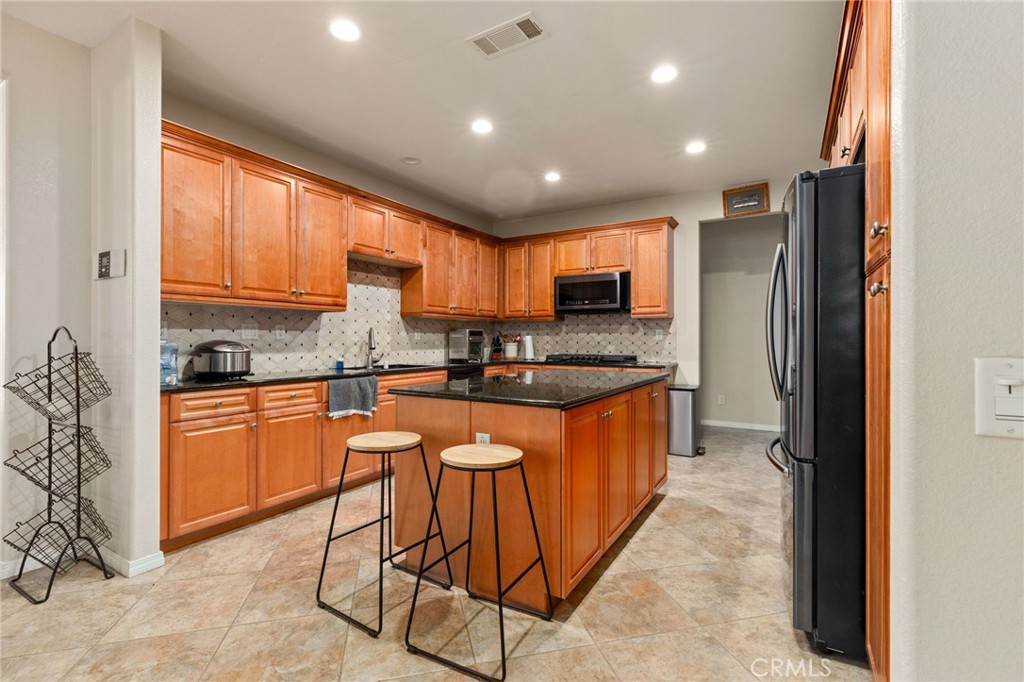 30355 Lamplighter Lane Menifee, CA 92584 - Photo 6 of 31 a kitchen with stainless steel appliances granite countertop wooden cabinets a stove a sink and a refrigerator