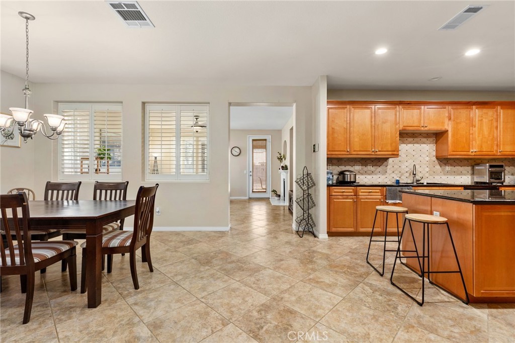 30355 Lamplighter Lane Menifee, CA 92584 - Photo 10 of 31 a kitchen with stainless steel appliances granite countertop a stove a sink a dining table and chairs
