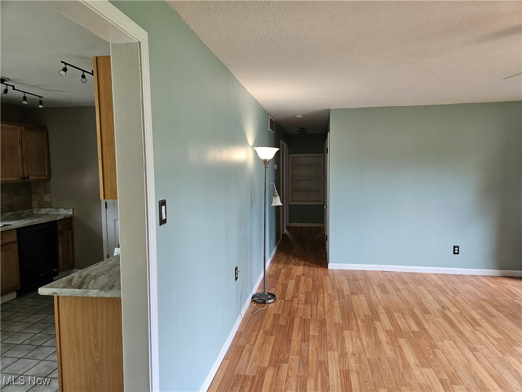 1895 Sandgate Road Madison, OH 44057 - Photo 10 of 16 Spare room featuring light wood finished floors, track lighting, baseboards, and a textured ceiling