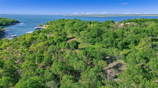 an aerial view of a residential houses with outdoor space and trees all around