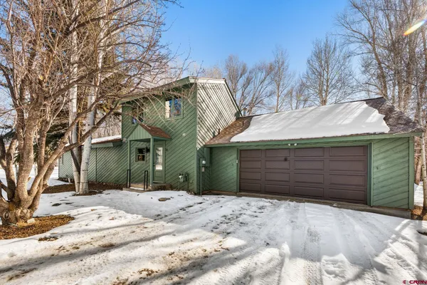 a front view of a house with a yard covered with snow
