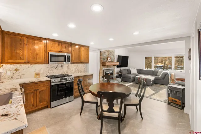 a kitchen with kitchen island a dining table chairs stainless steel appliances and cabinets