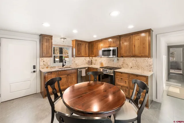 a kitchen with stainless steel appliances granite countertop a stove a sink a microwave a dining table and chairs
