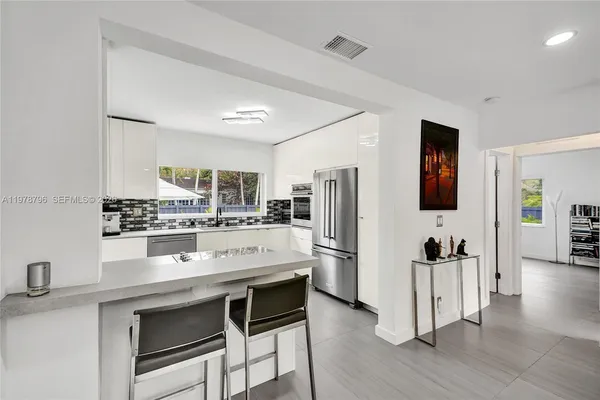 a kitchen with stainless steel appliances kitchen island granite countertop a refrigerator and microwave