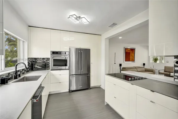 a kitchen with refrigerator a sink and chairs