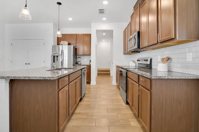 a kitchen with stainless steel appliances granite countertop a sink a stove and a refrigerator