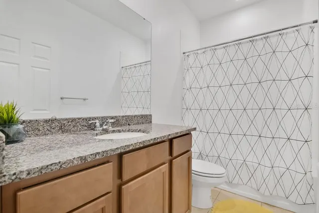 a bathroom with a granite countertop sink and a toilet