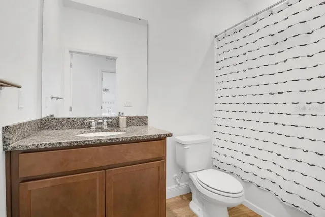 a bathroom with a granite countertop toilet a sink and a mirror