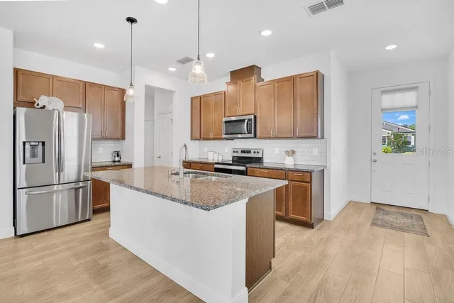 a kitchen with stainless steel appliances granite countertop a refrigerator a stove a sink and a microwave