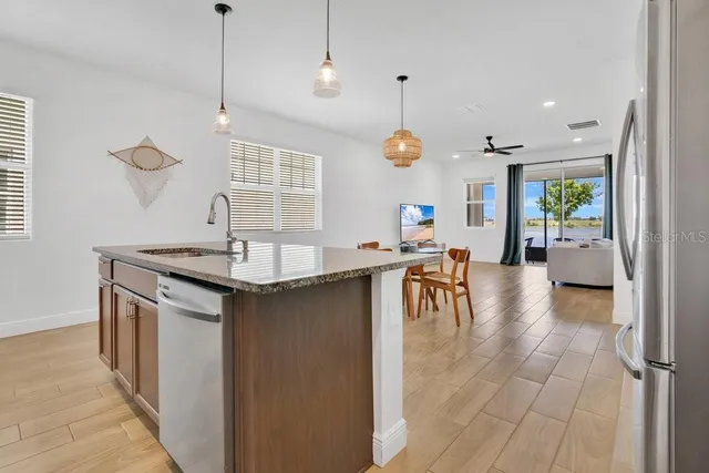 a kitchen with stainless steel appliances granite countertop a sink a stove and a wooden floors