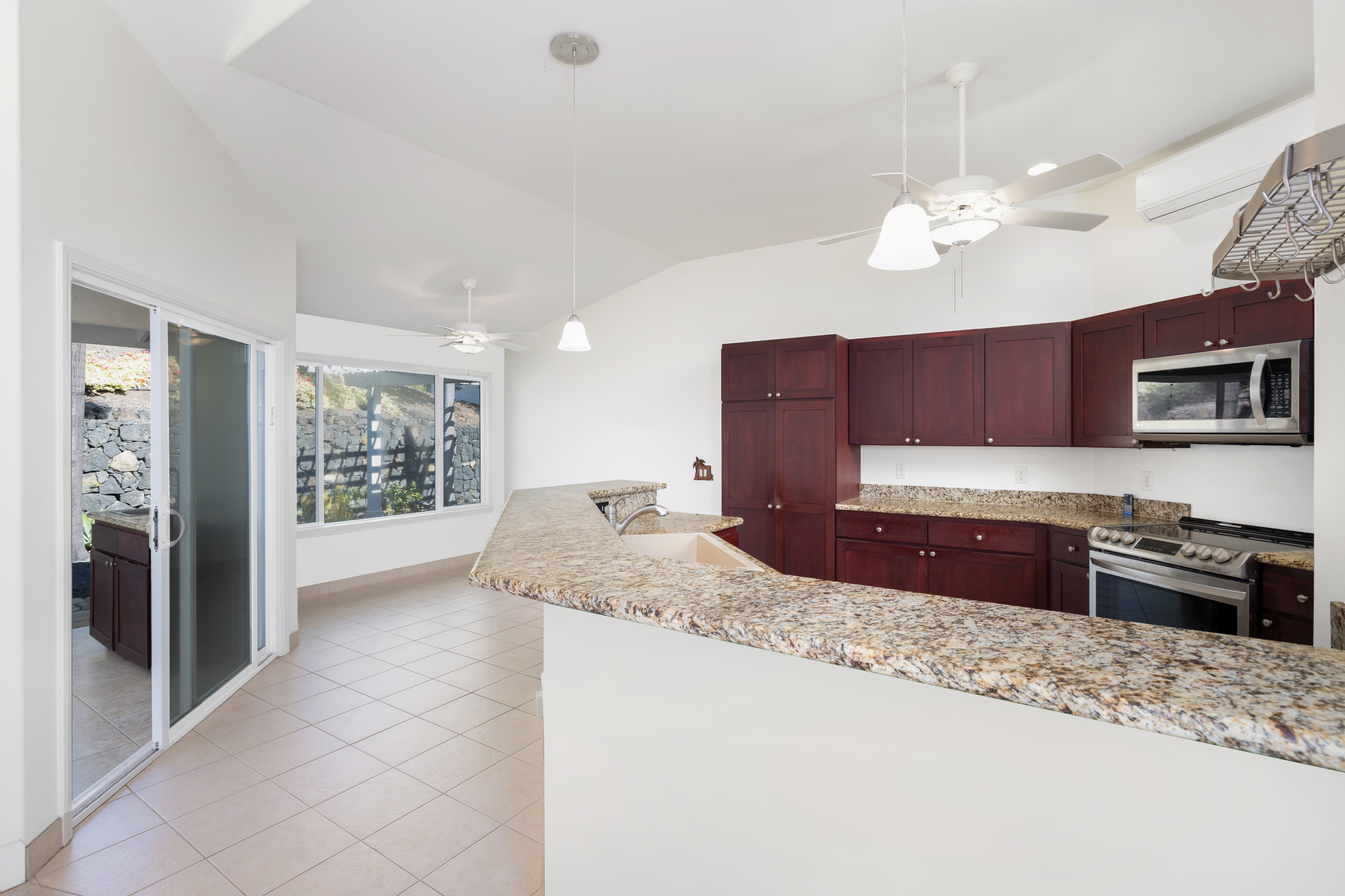 77-267 Hoomohala Road Kailua-Kona, HI 96740 - Photo 5 of 30 a large kitchen with granite countertop a refrigerator a stove a sink a oven with a dining table and chair