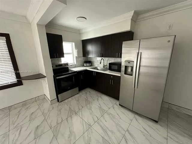 a kitchen with stainless steel appliances a sink a refrigerator a counter top space and cabinets