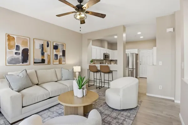 a living room with furniture kitchen view and a wooden floor