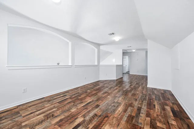 a view of empty room with wooden floor