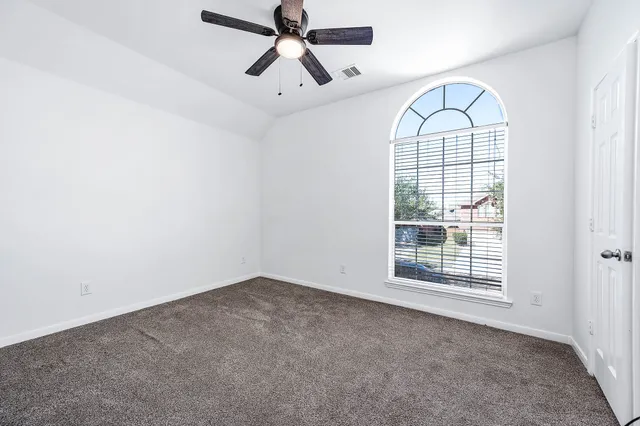 an empty room with windows and fan