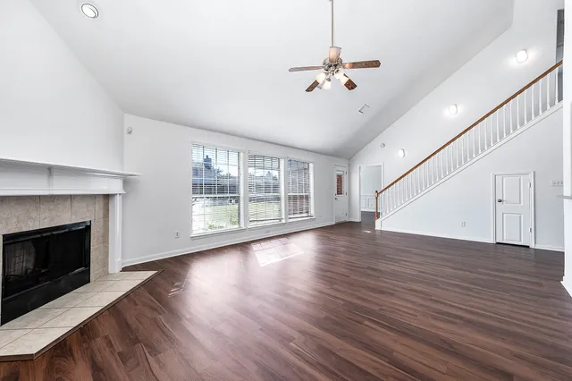 a view of an empty room with wooden floor and a fireplace