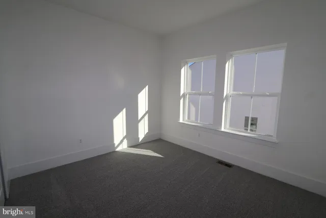 an empty room with wooden floor fireplace and windows