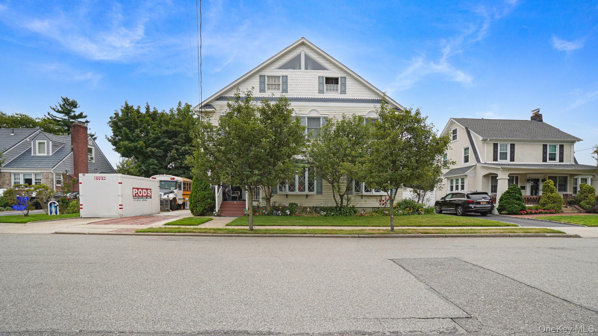 a front view of a house with a garden and trees