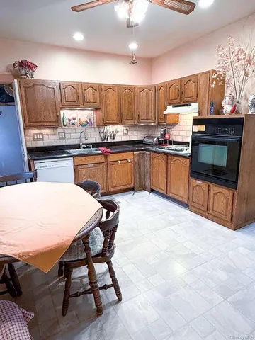 a kitchen with stainless steel appliances wooden cabinets granite counter tops a stove a sink and a dining table