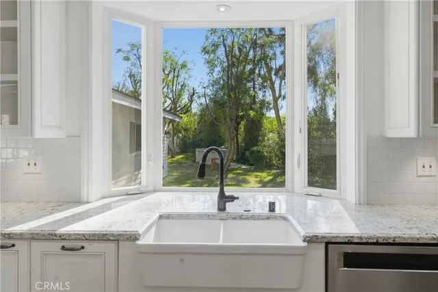 a kitchen with granite countertop a sink cabinets stainless steel appliances and a window
