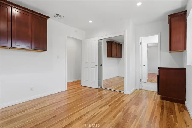 a view of empty room with wooden floor and fan