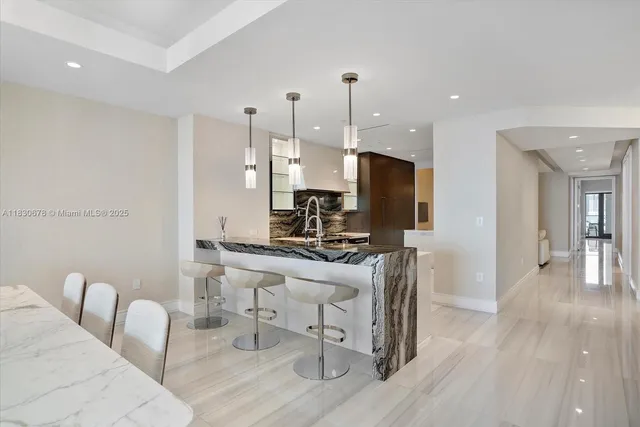 a kitchen with stainless steel appliances kitchen island granite countertop a table chairs and a wooden floor
