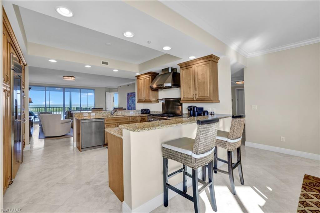 265 Indies Way, Unit 904 Naples, FL 34110 - Photo 6 of 19 a kitchen with stainless steel appliances kitchen island granite countertop a refrigerator a stove a sink dishwasher with a dining table and chairs