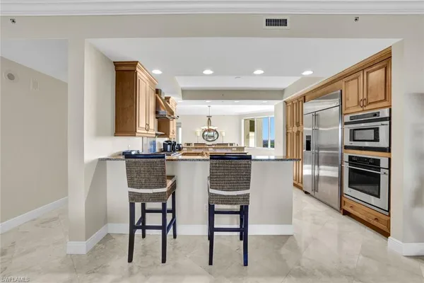 a kitchen with stainless steel appliances kitchen island granite top and refrigerator