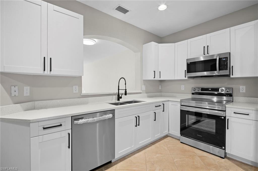 9648 Roundstone Circle Fort Myers, FL 33967 - Photo 9 of 30 a kitchen with white cabinets stainless steel appliances and sink