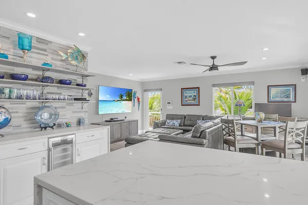 a living room with stainless steel appliances kitchen island granite countertop a stove a sink a dining table and chairs with wooden floor