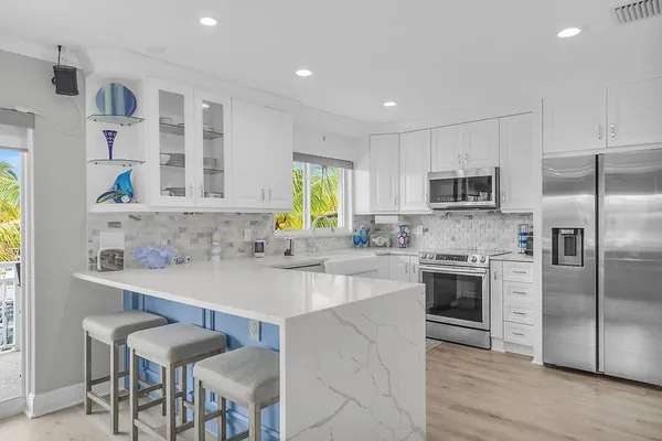 a kitchen with stainless steel appliances a sink a stove a refrigerator cabinets and a dining table with wooden floor