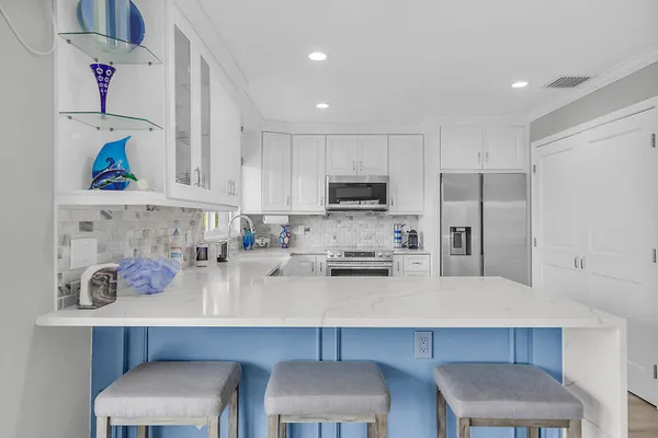 a kitchen with stainless steel appliances a dining table chairs refrigerator and sink