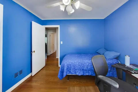 a bedroom with a chair and wooden floor