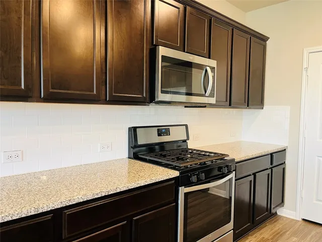 a kitchen with granite countertop wooden cabinets a refrigerator and a sink