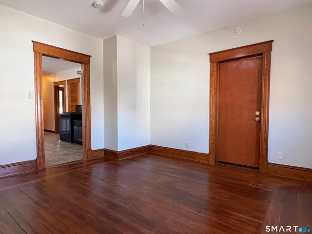 a view of an empty room with wooden floor and closet