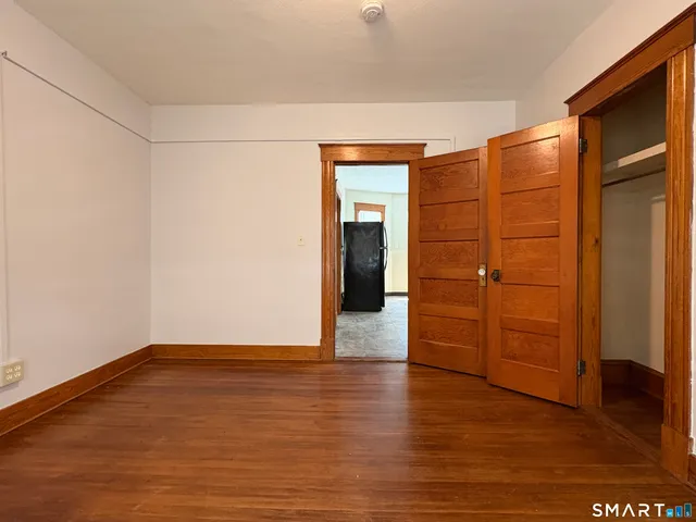 a view of an empty room with wooden floor and closet
