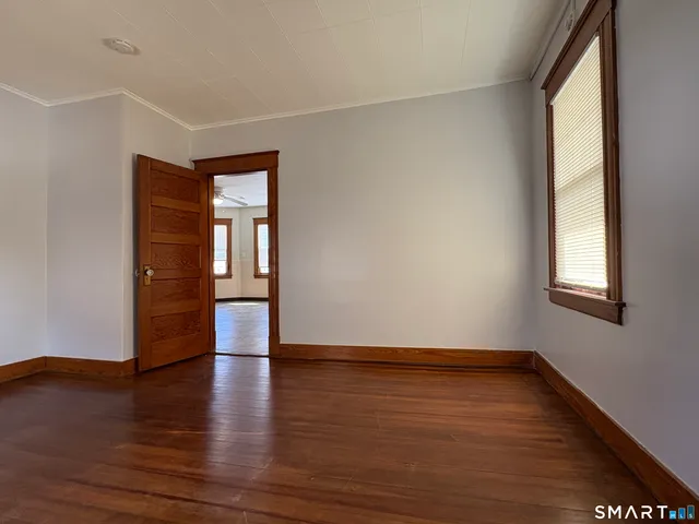 a view of an empty room with wooden floor and a window