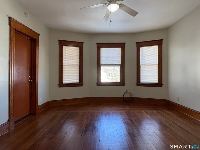 a view of an empty room with wooden floor and a window