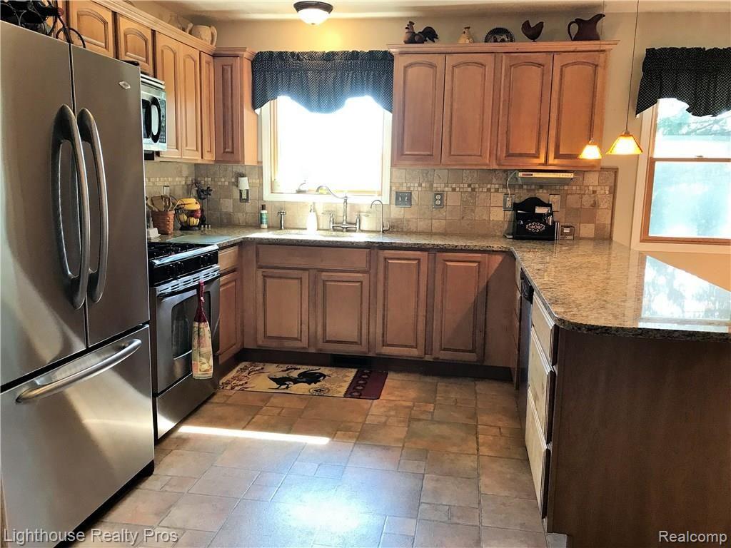 7150 Denton Hill Road Fenton, MI 48430 - Photo 6 of 47 Updated kitchen with ample hickory cabinets, granite, and tile back splash.