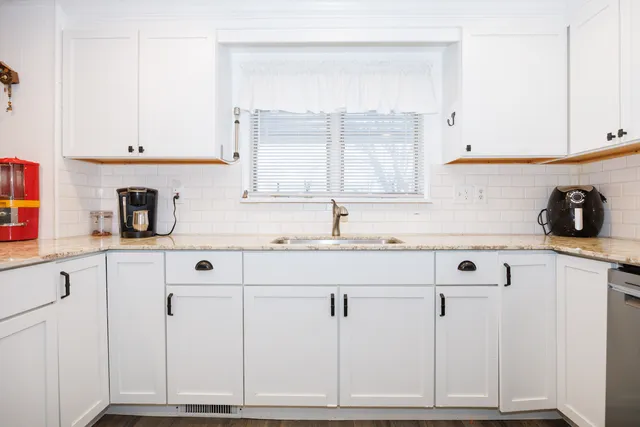a kitchen with granite countertop white cabinets and sink