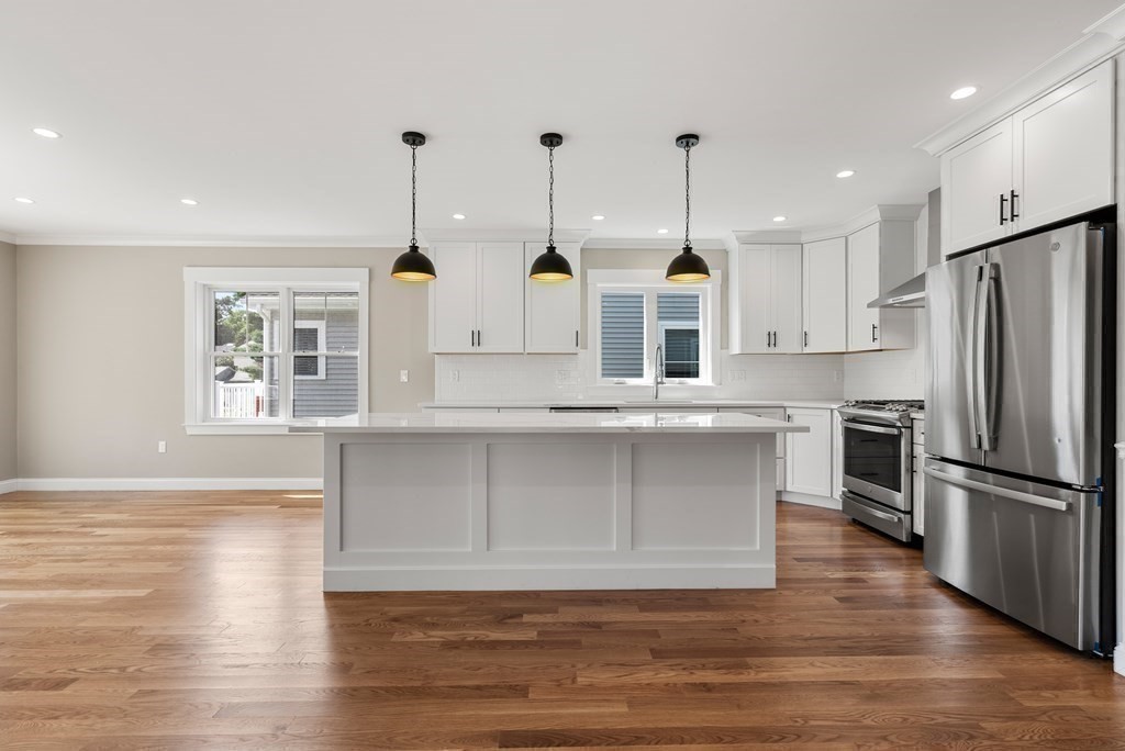 38 Gregory Street Waltham, MA 02451 - Photo 7 of 21 a large kitchen with granite countertop a stove a sink dishwasher a refrigerator and white cabinets with wooden floor
