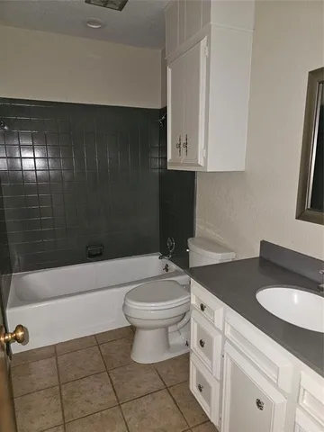 a bathroom with a granite countertop sink a toilet and bathtub