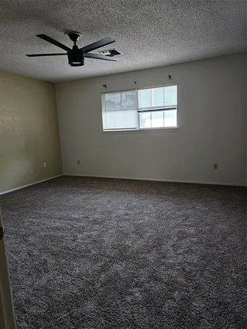 an empty room with a ceiling fan and window