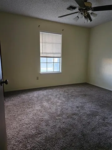 an empty room with a ceiling fan and window
