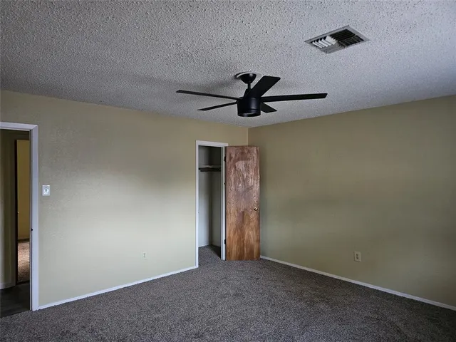 an empty room with closet and ceiling fan