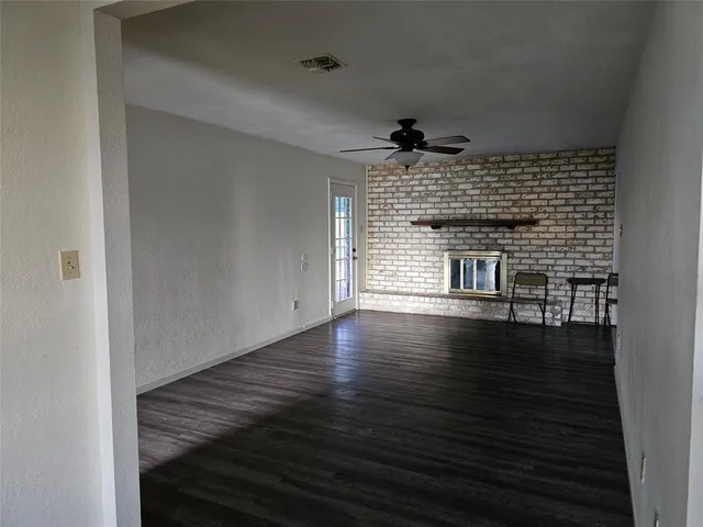 a view of empty room with wooden floor and fireplace