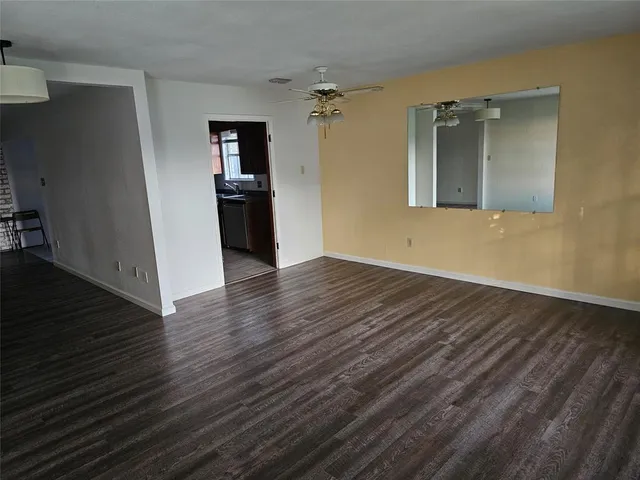 a view of a hallway with wooden floor and a kitchen