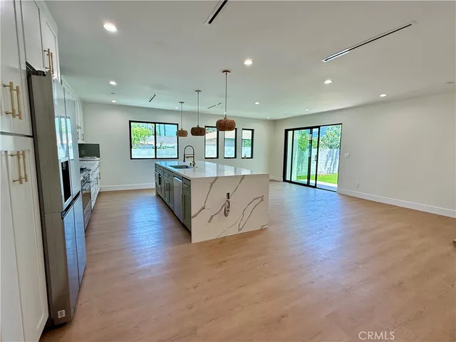 a large kitchen with stainless steel appliances granite countertop a large counter top a refrigerator and cabinets