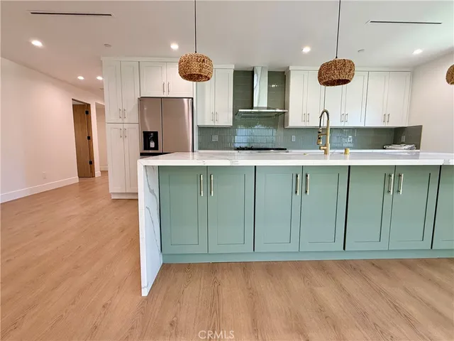 a kitchen with a sink a refrigerator and wooden floor